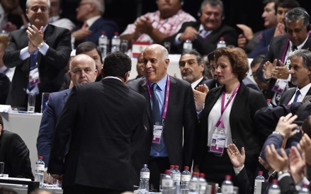 Ofer Eini (de dos), président et secrétaire général de l'Association de football d'Israël (IFA) serrant la main de Jibril Rajoub (au centre), président de la Fédération palestinienne de football lors du 65e Congrès de la FIFA à Zurich, le 29 mai 2015
(Crédit : AFP PHOTO / MICHAEL Buholzer) Ofer Eini (de dos), président et secrétaire général de l'Association de football d'Israël (IFA) serrant la main de Jibril Rajoub (au centre), président de la Fédération palestinienne de football lors du 65e Congrès de la FIFA à Zurich, le 29 mai 2015
(Crédit : AFP PHOTO / MICHAEL Buholzer)