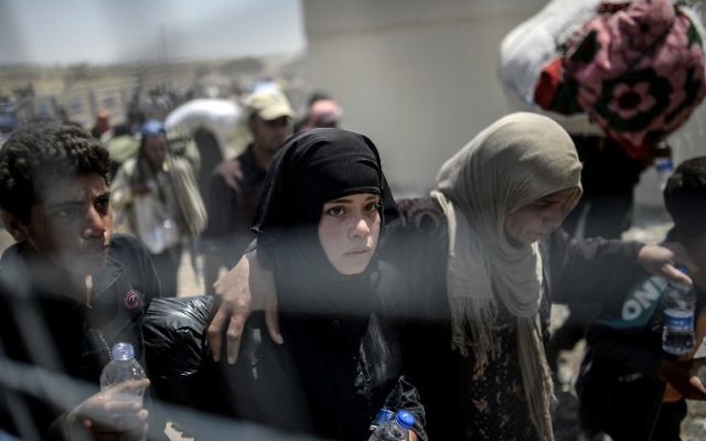 Les Syriens fuyant la guerre en se rendant au point de passage de la frontière Akcakale, dans la province de Sanliurfa, le 15 juin 2015. La Turquie a annoncé qu'elle prenait des mesures pour limiter le flux de réfugiés syriens sur son territoire après un afflux de milliers d'autres au cours des derniers jours en raison des combats entre les Kurdes et les djihadistes. En vertu d'une politique de « porte ouverte », la Turquie a accueilli près de 1,8 million de réfugiés syriens depuis le bébut du conflit en Syrie en 2011 (Crédit : AFP PHOTO / BULENT KILIC) Les Syriens fuyant la guerre en se rendant au point de passage de la frontière Akcakale, dans la province de Sanliurfa, le 15 juin 2015. La Turquie a annoncé qu'elle prenait des mesures pour limiter le flux de réfugiés syriens sur son territoire après un afflux de milliers d'autres au cours des derniers jours en raison des combats entre les Kurdes et les djihadistes. En vertu d'une politique de « porte ouverte », la Turquie a accueilli près de 1,8 million de réfugiés syriens depuis le bébut du conflit en Syrie en 2011 (Crédit : AFP PHOTO / BULENT KILIC)