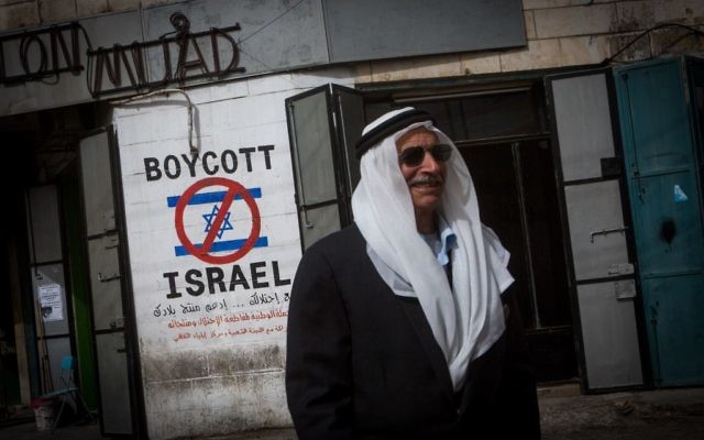 Un Palestinien marche près d'un graffiti demandant le boycott d'Israël dans la ville de Bethléem en Cisjordanie 11 février 2015 (Crédit : Miriam Alster / Flash90)