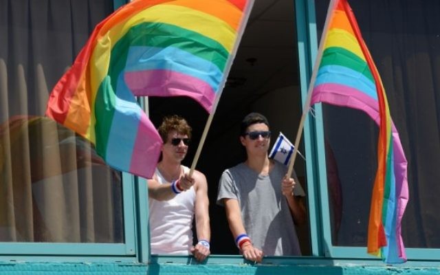 Des hommes agitant des drapeaux à la Gay Pride de Tel-Aviv le 12 juin 2015 (Crédit : Flash90 / Gili Yaar)