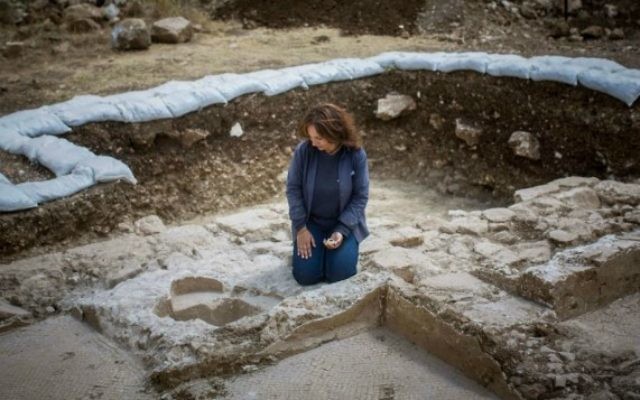 Annette Nagar, de l'Autorité des antiquités, regarde les fonts baptismaux de l'église de l'époque byzantine découverte à Abu Ghosh lors des travaux d'agrandissement et de modernisation de l'autoroute Jérusalem-Tel Aviv, en juin 2015 (Yonatan Sindel / Flash90)