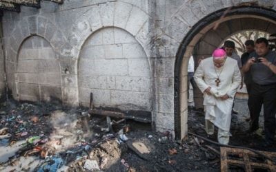 Un prêtre inspecte les dommages causés à l'Eglise de la Multiplication, à Tabgha, sur le lac de Tibériade, qui a  pris feu dans ce que la police suspecte être un incendie criminel, 18 juin 2015 (Crédits : Basel Awidat / Flash90)