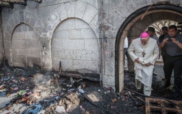 Un prêtre inspecte les dommages causés à l'Eglise de la Multiplication, à Tabgha, sur le lac de Tibériade, qui a  pris feu dans ce que la police suspecte être un incendie criminel, 18 juin 2015 (Crédits : Basel Awidat / Flash90)