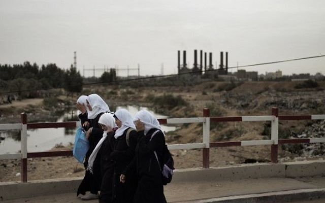 Des écolières palestiniennes traversant un pont dans la bande de Gaza, alors que la silhouette de la centrale électrique de la bande de Gaza est vu en l'arrière-plan. Photo d'archives (Crédit : Marco Longari / AFP) Des écolières palestiniennes traversant un pont dans la bande de Gaza, alors que la silhouette de la centrale électrique de la bande de Gaza est vu en l'arrière-plan. Photo d'archives (Crédit : Marco Longari / AFP)