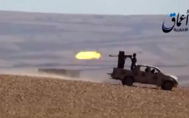 Des combattants du groupe Etat islamique tirant à partir d'un véhicule blindé sur une route menant à Ain al-Arab (Kobané), à la frontière entre la Syrie et la Turquie, capture d'écran YouTube (Crédit : AFP / HO / AAMAQ AGENCE DE NOUVELLES) Des combattants du groupe Etat islamique tirant à partir d'un véhicule blindé sur une route menant à Ain al-Arab (Kobané), à la frontière entre la Syrie et la Turquie, capture d'écran YouTube (Crédit : AFP / HO / AAMAQ AGENCE DE NOUVELLES)