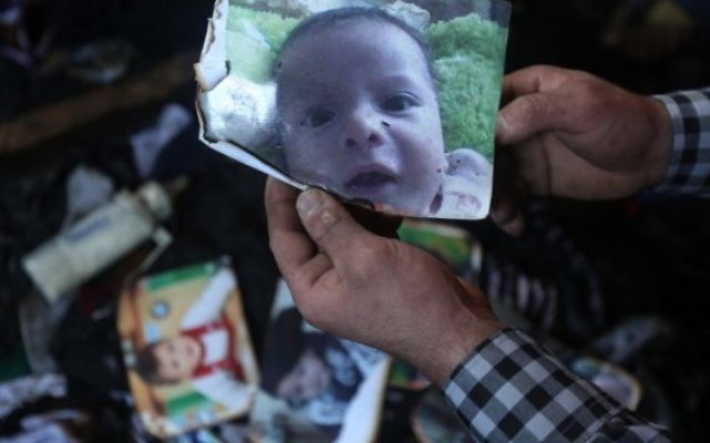 Un homme montre une photo de l'enfant palestinien Ali Saad Dawabsha de 18 mois qui est mort quand sa maison a été incendiée par des extrémistes juifs présumés dans le village cisjordanien de Duma le 31 juillet 2015 (Crédit photo: Jaafar Ashtiyeh / AFP) Un homme montre une photo de l'enfant palestinien Ali Saad Dawabsha de 18 mois qui est mort quand sa maison a été incendiée par des extrémistes juifs présumés dans le village cisjordanien de Duma le 31 juillet 2015 (Crédit photo: Jaafar Ashtiyeh / AFP)
