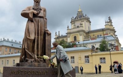 Une femme dépose des fleurs devant le monument pour l'Archevêque métropolitain de l'Eglise catholique grecque ukrainienne, Andriy Sheptytsky (1865-1944) après son inauguration pour le 150e anniversaire de sa naissance le 29 juillet 2015 dans le ville ukrainienne de Lviv (Crédit : AFP PHOTO / YURIY DYACHYSHYN)