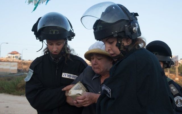 Les forces de sécurité israéliennes emmènent une résidente d'implantation venue pour manifester contre la démolition de deux immeubles d'habitation dans l'implantation juive de Beit El, le 28 juillet 2015 (Crédit : Nati Shohat / FLASH90) Les forces de sécurité israéliennes emmènent une résidente d'implantation venue pour manifester contre la démolition de deux immeubles d'habitation dans l'implantation juive de Beit El, le 28 juillet 2015 (Crédit : Nati Shohat / FLASH90)