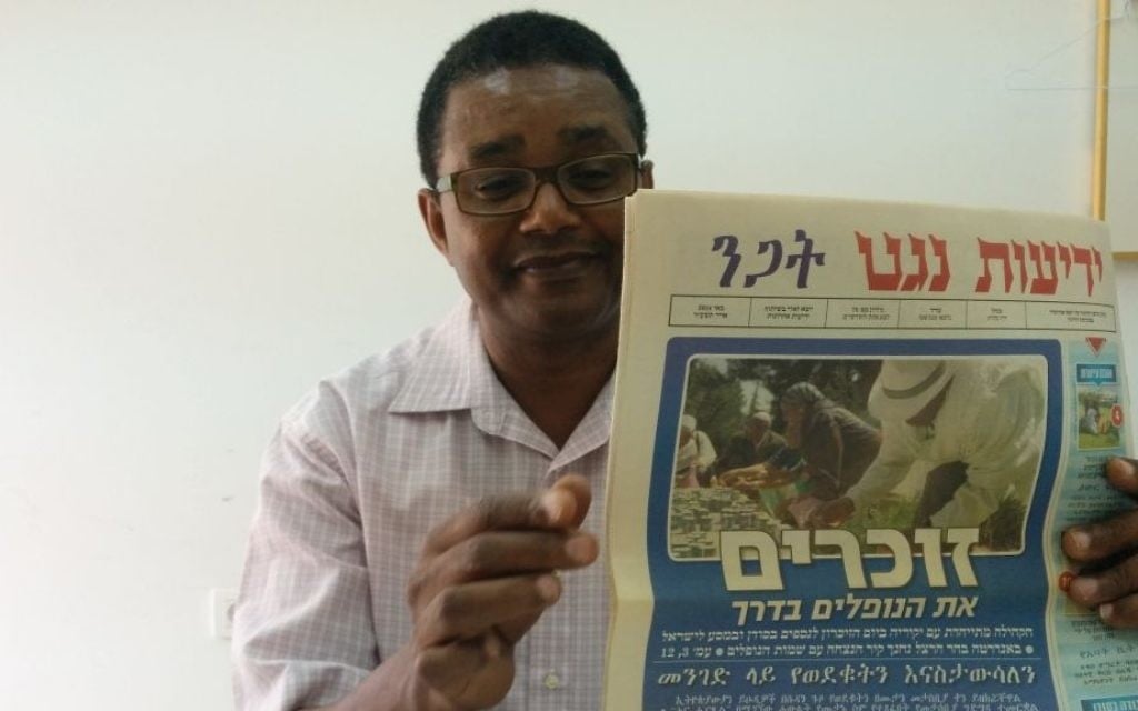 Dr Anbessa Teferra, professeur de langues sémitiques à l'université de Tel-Aviv, tient un numéro de Yedioth Negat, journal en amharique. (Ilan Ben Zion / Times of Israel) Dr Anbessa Teferra, professeur de langues sémitiques à l'université de Tel-Aviv, tient un numéro de Yedioth Negat, journal en amharique. (Ilan Ben Zion / Times of Israel)