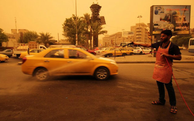 Un travailleur irakienne asperge le sol d'eau pendant une tempête de sable dans la capitale Bagdad le 1er septembre 2015 (Crédit : AFP Photo / Haidar Mohammed Ali) Un travailleur irakienne asperge le sol d'eau pendant une tempête de sable dans la capitale Bagdad le 1er septembre 2015 (Crédit : AFP Photo / Haidar Mohammed Ali)