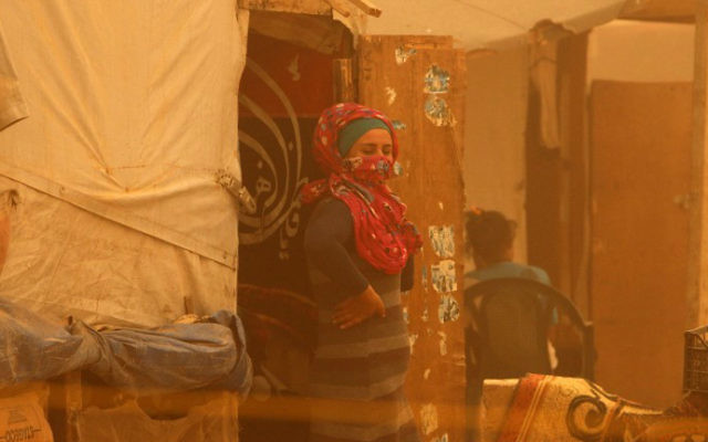 Une femme syrienne se tenant à l'extérieur de sa tente, entourée par un nuage de poussière pendant une tempête de sable le 7 septembre 2015 au camp de réfugiés en périphérie de la ville libanaise de Baalbek (Crédit : AFP PHOTO / STR) Une femme syrienne se tenant à l'extérieur de sa tente, entourée par un nuage de poussière pendant une tempête de sable le 7 septembre 2015 au camp de réfugiés en périphérie de la ville libanaise de Baalbek (Crédit : AFP PHOTO / STR)