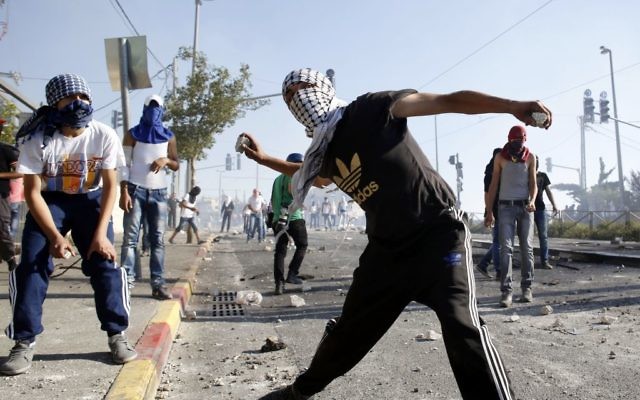 Des émeutiers palestiniens masqués jetant des pierres sur la police israélienne lors d'affrontements dans le quartier de Shuafat à Jérusalem-Est, le 3 juillet 2014 (Crédit photo: Sliman Khader / Flash90)