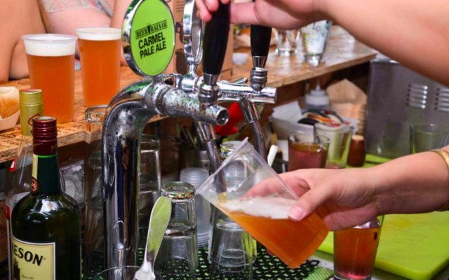 Un barman servant du Carmel Pale Ale, une bière  israélienne (Crédit :  Beer Bazaar)