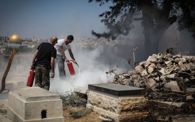 Les forces de sécurité tentent d'éteindre un incendie qui a éclaté dans le cimetière juif du Mont des Oliviers, où plusieurs pierres tombales auraient été profanées et mises à feu pendant la nuit, le 2 septembre 2015 [Hadas Parush / Flash90]