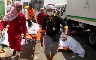 Le personnel d'urgence saoudiens et les pèlerins du Hadj en train d'évacuer un blessé de l'endroit où des centaines de personnes ont été tuées dans une bousculade à Mina, près de la ville sainte de La Mecque, pendant le hajj annuel à en Arabie Saoudite le 24 septembre 2015 (Crédit : AFP / STR)