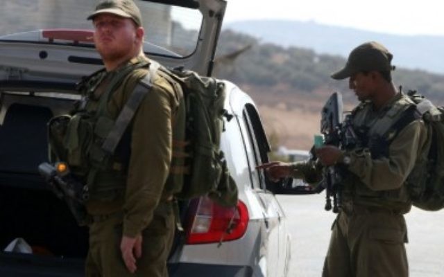Les soldats israéliens inspectent une voiture palestinienne à un checkpoint près du village cisjordanien de Beit Furik, à l'est de Naplouse le 2 octobre 2015.. (Crédit : Jaafar Ashtiyeh/AFP) Les soldats israéliens inspectent une voiture palestinienne à un checkpoint près du village cisjordanien de Beit Furik, à l'est de Naplouse le 2 octobre 2015.. (Crédit : Jaafar Ashtiyeh/AFP)
