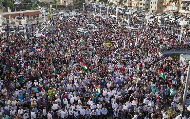 Les Arabes israéliens arabes  brandissant des drapeaux palestiniens et prenant part à une grande manifestation dans le cadre d'une grève générale organisée pour soutenir les Palestiniens qui appellent à une "journée de la colère" le 13 octobre 2015 dans le village israélo-arabe de Sakhnin (Crédit : AFP PHOTO / JACK GUEZ)