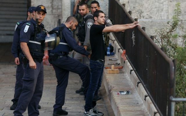 Un policier israélien fouille un jeune homme palestinien à l'entrée de la Porte de Damas de la Vieille Ville de Jérusalem le 13 octobre 2015. (Crédit : AFP PHOTO / AHMAD GHARABLI) Un policier israélien fouille un jeune homme palestinien à l'entrée de la Porte de Damas de la Vieille Ville de Jérusalem le 13 octobre 2015. (Crédit : AFP PHOTO / AHMAD GHARABLI)