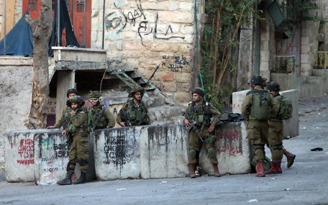 Les forces de sécurité israéliennes montent la garde près de l'endroit où un Palestinien a tenté de poignarder un soldat israélien avant d'être abattu, dans la ville d'Hébron en Cisjordanie, le mercredi 28 octobre 2015 (Crédit : AFP PHOTO / HAZEM BADER) Les forces de sécurité israéliennes montent la garde près de l'endroit où un Palestinien a tenté de poignarder un soldat israélien avant d'être abattu, dans la ville d'Hébron en Cisjordanie, le mercredi 28 octobre 2015 (Crédit : AFP PHOTO / HAZEM BADER)