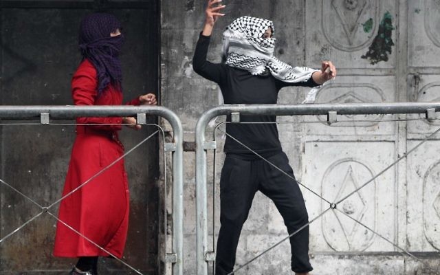 Une jeune femme palestinienne jette des pierres vers les forces de sécurité israéliennes lors d'affrontements dans la ville d'Hébron en Cisjordanie, le 7 octobre 2015. (Crédit : AFP PHOTO / HAZEM BADER Une jeune femme palestinienne jette des pierres vers les forces de sécurité israéliennes lors d'affrontements dans la ville d'Hébron en Cisjordanie, le 7 octobre 2015. (Crédit : AFP PHOTO / HAZEM BADER