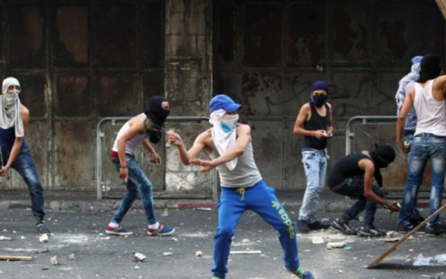 De jeunes Palestiniens lancent des pierres vers les forces de sécurité israéliennes lors d'affrontements dans la ville d'Hébron en Cisjordanie, le 4 octobre, 2015. (Crédit : AFP / HAZEM BADER) De jeunes Palestiniens lancent des pierres vers les forces de sécurité israéliennes lors d'affrontements dans la ville d'Hébron en Cisjordanie, le 4 octobre, 2015. (Crédit : AFP / HAZEM BADER)