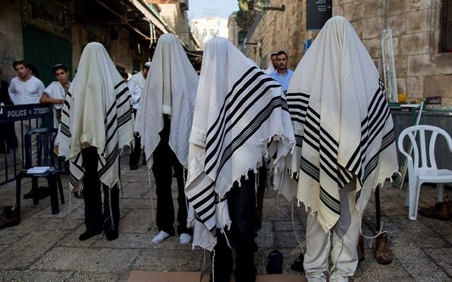 Des hommes prient sur le lieu de l'attaque où deux Israéliens ont ét tués par un terroriste palestinien la veille (Crédit : Flash 90) Des hommes prient sur le lieu de l'attaque où deux Israéliens ont ét tués par un terroriste palestinien la veille (Crédit : Flash 90)