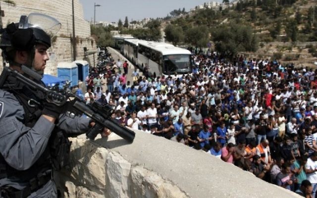 Un policier monte la garde alors que des Palestiniens, qui ont été empêchés de pénétrer dans l'enceinte du mont du Temple en raison de restrictions d'âge sur des hommes musulmans pour participer à la prière du vendredi, prient à la Porte des Lions dans la Vieille Ville de Jérusalem, le 2 octobre 2015 (Crédit photo: Thomas Coex / AFP)