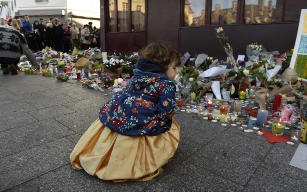 Une enfant visite un site commémoratif le 15 novembre à 2015 à l'extérieur du restaurant Petit Cambodge, dans le 10ème arrondissement de Paris, pour les victimes des attaques terroristes du 13 novembre à Paris. (Crédit : AFP)