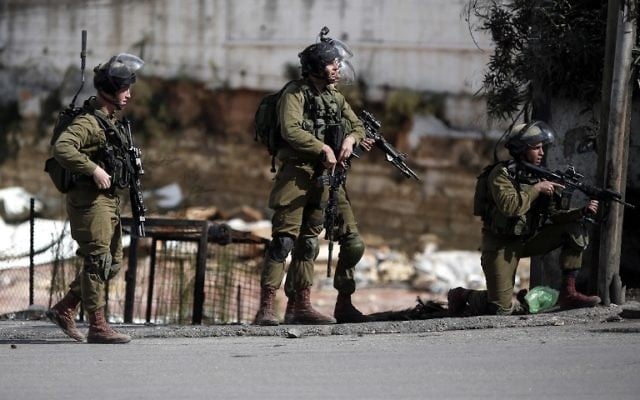 Les forces de sécurité israéliennes se tiennent dans une rue lors d'affrontements avec des manifestants palestiniens dans la ville cisjordanienne de Hébron, le 30 octobre 2015 (Crédit : AFP / Thomas Coex) Les forces de sécurité israéliennes se tiennent dans une rue lors d'affrontements avec des manifestants palestiniens dans la ville cisjordanienne de Hébron, le 30 octobre 2015 (Crédit : AFP / Thomas Coex)