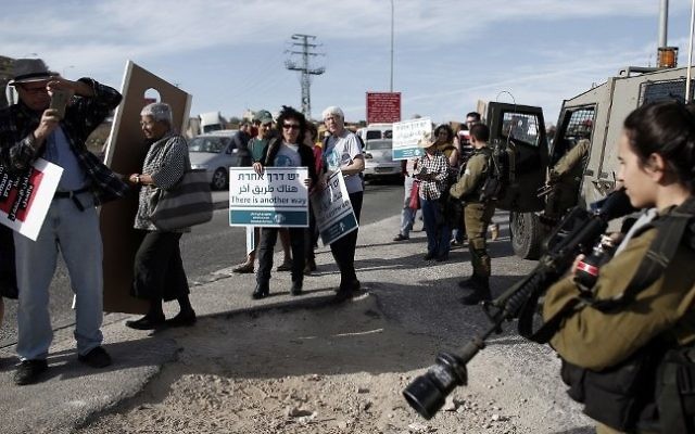Les militant pour la paix israéliens et palestiniens passant devant les troupes de l'armée lors d'une manifestation en Cisjordanie le 27 novembre 2015 (Crédit : AFP PHOTO / THOMAS COEX) Les militant pour la paix israéliens et palestiniens passant devant les troupes de l'armée lors d'une manifestation en Cisjordanie le 27 novembre 2015 (Crédit : AFP PHOTO / THOMAS COEX)