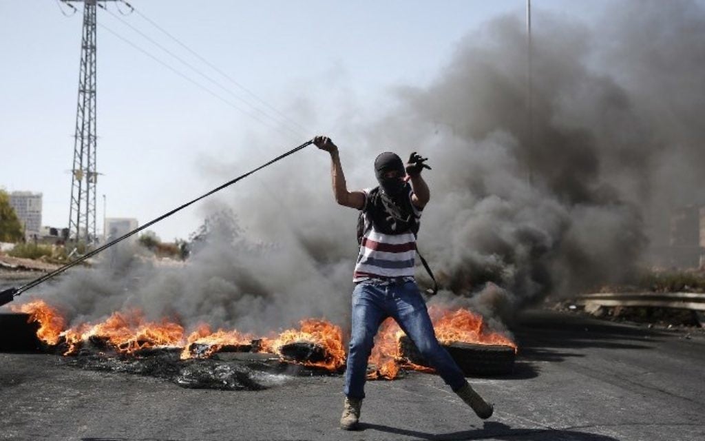 Un émeutier palestinien utilise un lance-pierre pour jeter des pierres vers les forces de sécurité israéliennes lors d'affrontements à Beit El, près de la ville cisjordanienne de Ramallah, le 11 octobre 2015 (Crédit : AFP / Abbas Momani) Un émeutier palestinien utilise un lance-pierre pour jeter des pierres vers les forces de sécurité israéliennes lors d'affrontements à Beit El, près de la ville cisjordanienne de Ramallah, le 11 octobre 2015 (Crédit : AFP / Abbas Momani)