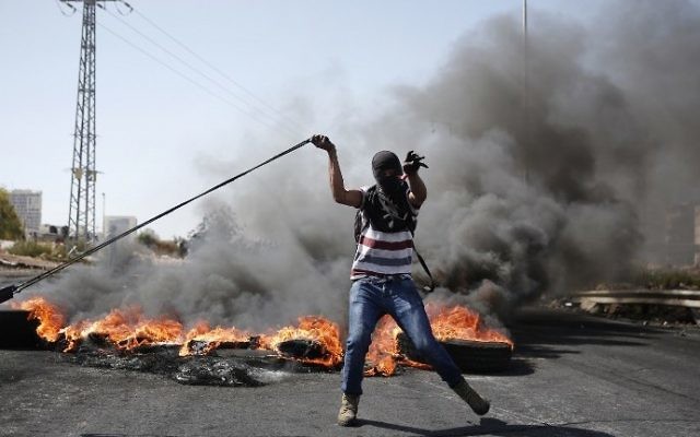 Un émeutier palestinien utilise un lance-pierre pour jeter des pierres vers les forces de sécurité israéliennes lors d'affrontements à Beit El, près de la ville cisjordanienne de Ramallah, le 11 octobre 2015 (Crédit : AFP / Abbas Momani)