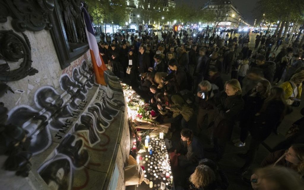Des gens allument des bougies dans un mémorial de fortune en hommage aux victimes des attaques de Paris le 14 novembre 2015 au lieu sur la place de la République à Paris. les djihadistes de l'Etat Islamique ont revendiqué une série d'attaques coordonnées par des hommes armés et des kamikazes à Paris qui ont tué au moins 129 (Crédit : AFP PHOTO / JOEL SAGET)