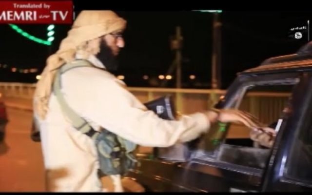 Un membre de l'EI distribue des bonbons à un conducteur de voiture pour célébrer le crash de l'avion russe dans le Sinai (Crédit : capture d'écran MEMRI) Un membre de l'EI distribue des bonbons à un conducteur de voiture pour célébrer le crash de l'avion russe dans le Sinai (Crédit : capture d'écran MEMRI)