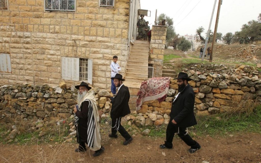Des Juifs ultra-orthodoxes passent devant une maison palestinienne fouillée par des soldats israéliens dans la ville de Hébron en Cisjordanie, le 7 novembre 2015 (Crédit photo: Hazem Bader / AFP) Des Juifs ultra-orthodoxes passent devant une maison palestinienne fouillée par des soldats israéliens dans la ville de Hébron en Cisjordanie, le 7 novembre 2015 (Crédit photo: Hazem Bader / AFP)