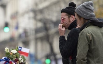 Le chanteur du groupe de rock américain Eagles of Death Metal, Jesse Hughes, (à guache) et le batteur Julian Dorio rendant hommage aux victimes des attentats du 13 novembre à Paris à un mémorial de fortune en face de la salle de concert du Bataclan à Paris le 8 décembre 2015 (Crédit : Miguel Medina / AFP)