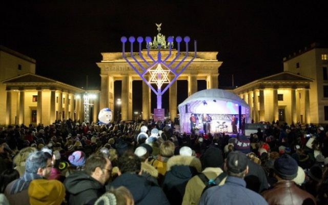 Les gens se tiennent devant un géant candélabre de Hanoucca en face de la Porte de Brandebourg à Berlin le 6 décembre 2015 au début de la fête juive de huit jours. (Crédit : AFP Photo / DPA / Jorg Carstensen) Les gens se tiennent devant un géant candélabre de Hanoucca en face de la Porte de Brandebourg à Berlin le 6 décembre 2015 au début de la fête juive de huit jours. (Crédit : AFP Photo / DPA / Jorg Carstensen)