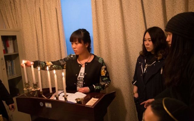 Des membres de la communauté juive chinoise de Kaifeng allume la ménorah le premier soir de Hanoukka, 6 décembre 2015. (Crédit : Shavei Israel)