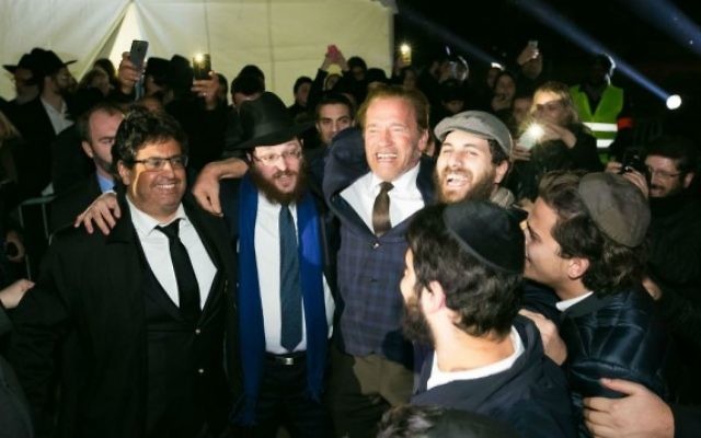 L'ancien gouverneur de Californie Arnold Schwarzenegger danse avec les rabbins Loubavitch à une cérémonie d'allumage de menorah publique au pied de la Tour Eiffel à Paris, le dimanche 6 décembre, 2015, la première nuit de la fête de huit jours. (Crédit : chabad.org/Thierry Guez) L'ancien gouverneur de Californie Arnold Schwarzenegger danse avec les rabbins Loubavitch à une cérémonie d'allumage de menorah publique au pied de la Tour Eiffel à Paris, le dimanche 6 décembre, 2015, la première nuit de la fête de huit jours. (Crédit : chabad.org/Thierry Guez)