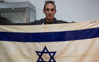 Une photo montrant un employé de  Kedem Auction House à Jérusalem montrant le drapeau du navire emblématique, le SS Exodus, le 15 novembre 2015 (Crédit : AFP / MENAHEM KAHANA)
