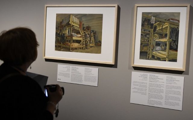 Une journaliste devant des peintures de l'exposition "L'art de l'Holocauste - 100 œuvres de la collection de Yad Vashem" à Berlin le 25 janvier 2016. (Crédit : AFP / TOBIAS SCHWARZ)