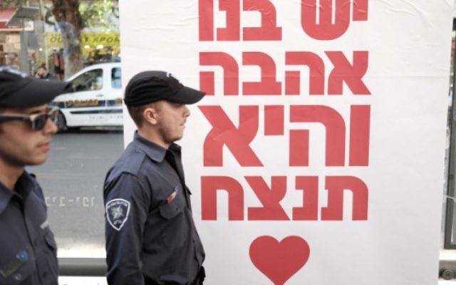 Les policiers marchent devant une affiche où l'on peut lire : "Nous avons de l'amour en nous, et il va gagner", lors d'une fête de rue le 15 janvier 2016 au bar Simta à Tel Aviv, où deux Israéliens ont été tués dans une fusillade le 1er janvier 2016. (Crédit : Tomer Neuberg / FLASH90)