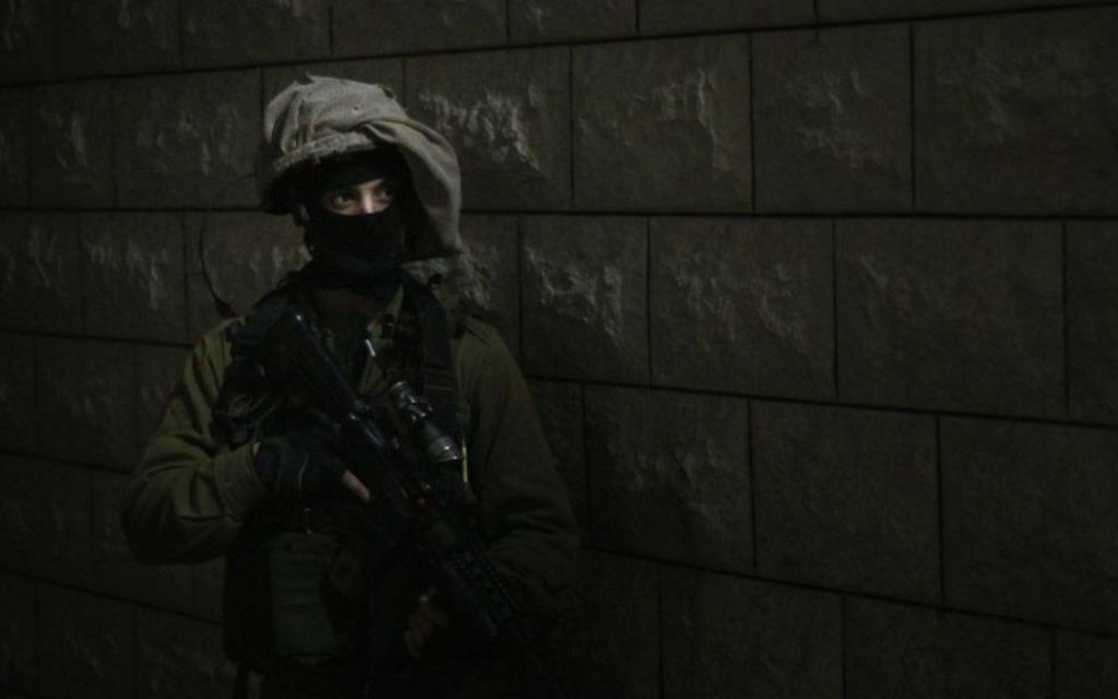 Un soldat se prépare à entrer dans la maison d'un adolescent palestinien, suspecté d'avoir jeter des pierres sur des soldats israéliens pendant une émeute à Qalqilya. Une équipe était déjà entrée dans la maison pour réveiller la famille, qui avait initialement affirmé que son fils n'était pas à la maison, le 14 janvier 2016. (Crédit : Judah Ari Gross/Times of Israel)