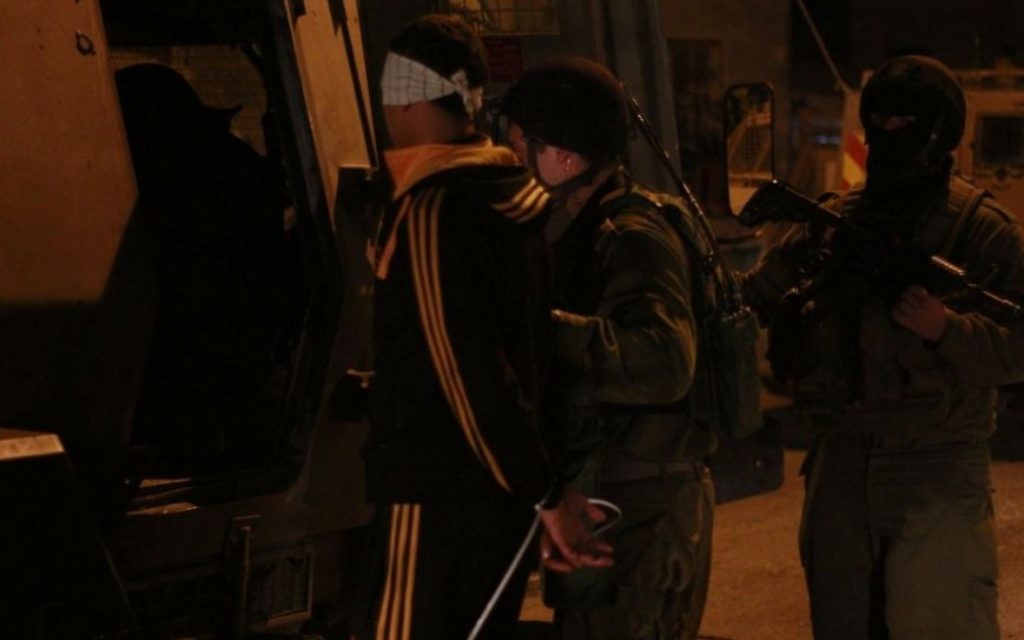 Des soldats embarquent l'un des suspects à l'arrière d'un Zeev, un grand véhicule blindé de transport de personnes, à Qalqilya le 14 janvier 2016. Le commandant des soldats, Lt. Col. Nimrod Cibulski, leur a fait éloigner l'adolescent palestinien de sa famille avant de lui attacher les mains et de lui bander les yeux, afin d'épargner au père du suspect la vision de son fils attaché, selon Cibulski. (Crédit : Judah Ari Gross/Times of Israel)