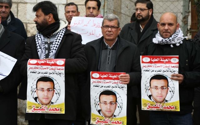 Des militants palestiniens avec des affiches pendant une manifestation pour la libération du journaliste palestinien Mohammed al-Qiq devant le siège de la Croix rouge de Ramallah, en Cisjordanie, le 27 janvier 2016. (Crédit : Flash90)