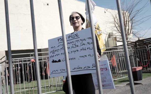 Une femme tient une pancarte contre le rassemblement des ONG de gauche dans le port de Tel Aviv le 5 février 2016. (Crédit : Tomer Neuberg / Flash90