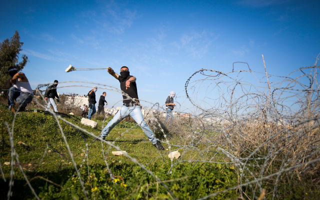 Palestinienne utilisant une fronde à lancer des pierres vers des soldats israéliens (hors du champ) lors d'affrontements près de la ville cisjordanienne de Ramallah, le 12 février 2016 (Crédit : Flash90) Palestinienne utilisant une fronde à lancer des pierres vers des soldats israéliens (hors du champ) lors d'affrontements près de la ville cisjordanienne de Ramallah, le 12 février 2016 (Crédit : Flash90)