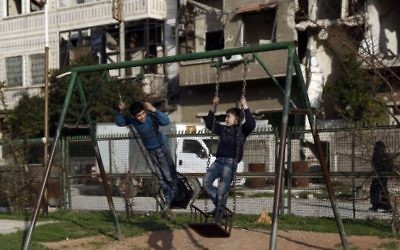 Des enfants syriens jouant à la balançoire dans un parc dans la ville de Douma tenue par les forces rebelles, à l'est de la capitale Damas, le 27 février 2016 (Crédit photo: Sameer Al-Doumy / AFP)