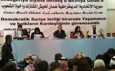 Aldar Khalil (C), du Mouvement pour une société démocratique, et le cheikh Hamad Sheikh Shihadeh (à droite), le chef du clan Naim dans le nord de la Syrie, lors d'une réunion de plus de 150 délégués kurdes, arabes, assyriens et d'autres parties dans la ville de Rmeilan, dans la province de Hasakah nord-est de la Syrie, où la décision a été prise d'établir une région fédérale, le 16 mars 2016 (Crédit : AFP / DELIL SOULEIMAN)