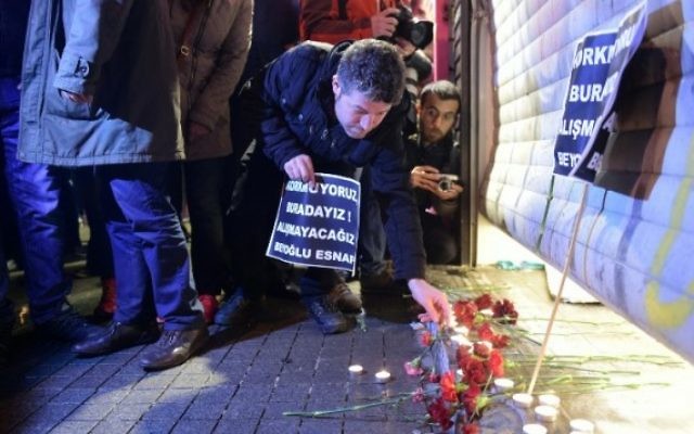 Un homme allume une bougie sur le site d'un attentat suicide dans la rue Istiklal, un quartier commerçant et touristique majeur, dans le centre d'Istanbul, le 19 mars 2016 (Crédit : AFP / BULENT KILIC)